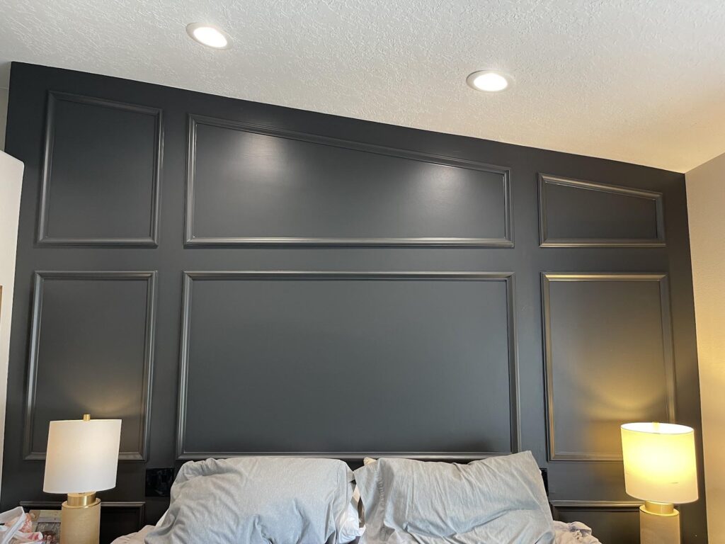 A modern bedroom featuring a black headboard against stylish gray walls