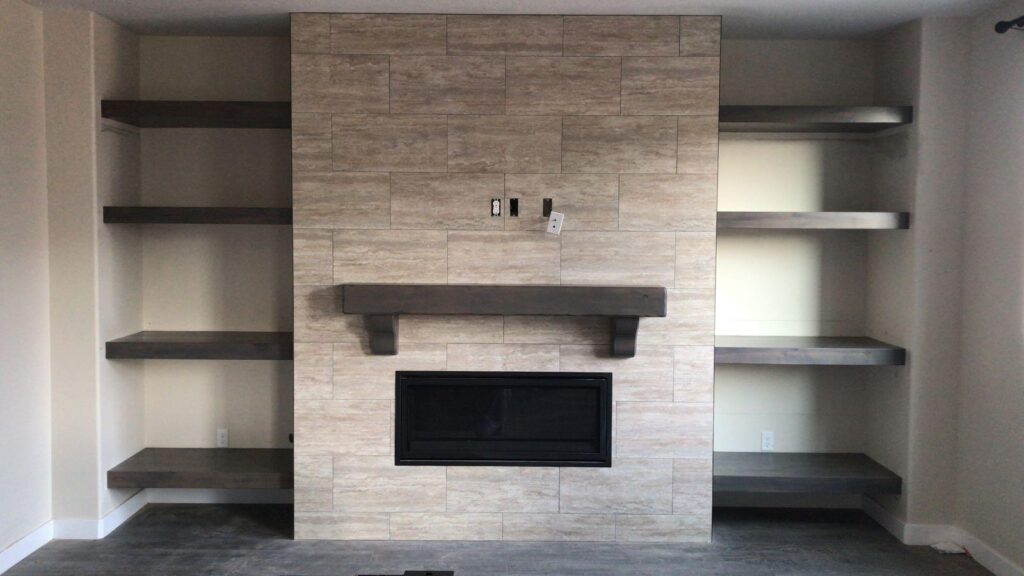 A warm fireplace surrounded by built in shelves displaying books and decorative objects