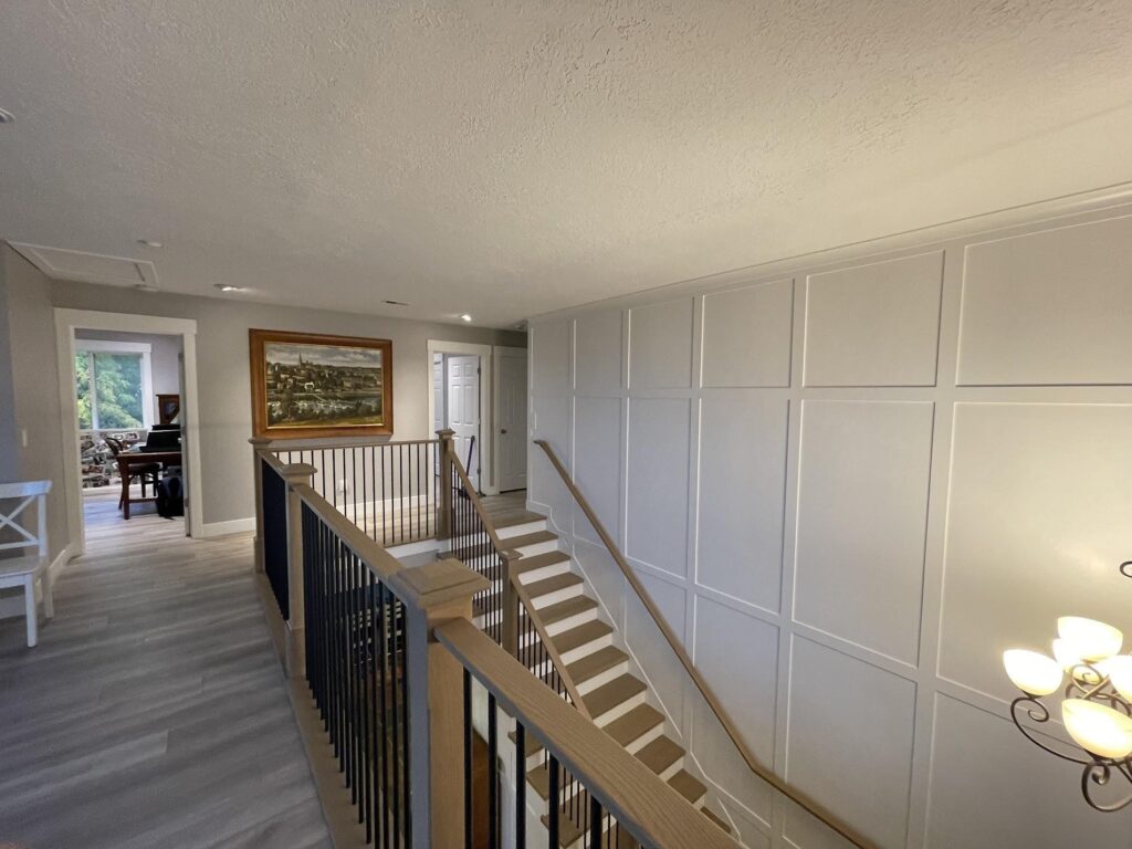 A hallway featuring white walls and a staircase leading to an upper level